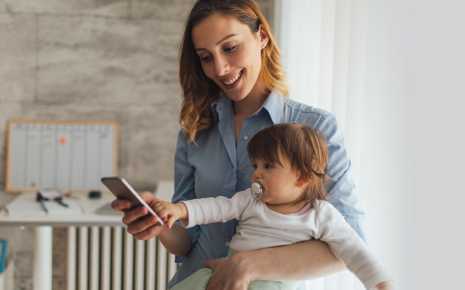 woman holding baby and scrolling through her iphone
